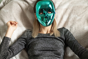 girl in a blue mask sits on a white armchair at home, closed face, privacy, masked