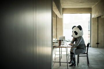 Woman with panda mask sitting in office, thinking