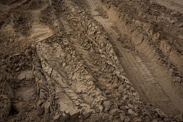Wheel trail on sandy ground from large transport, tractor on construction site, sandy road