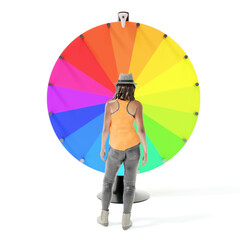 Miniature female figure in hip clothing looking at color wheel of fortune, isolated on white background - 462815122