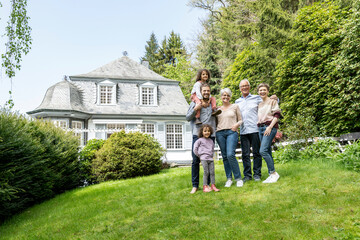 Happy extended family standing in garden of their home