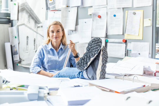 Woman relaxing at desk in office surrounded by paperwork