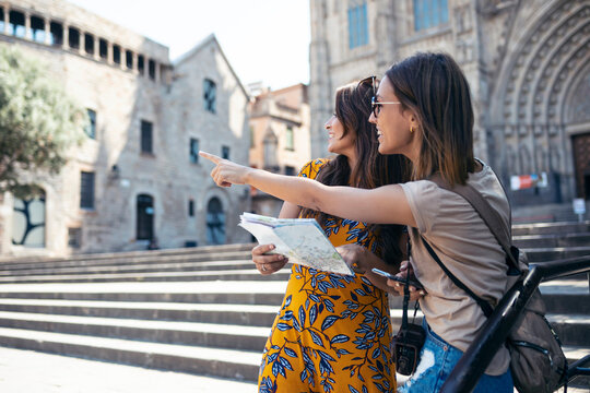 Friends studying map while standing at Barcelona Cathedral Square in Barcelona, Catalonia, Spain
