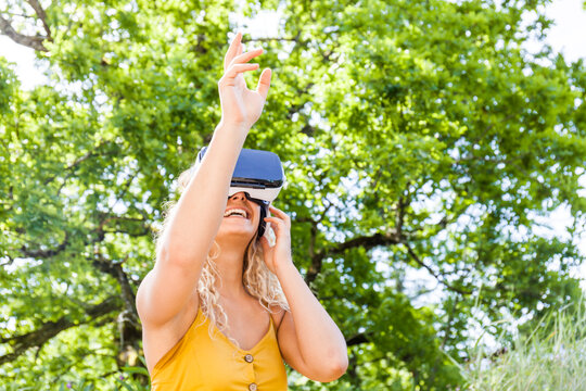 Young blond woman using virtual reality glasses outdoors