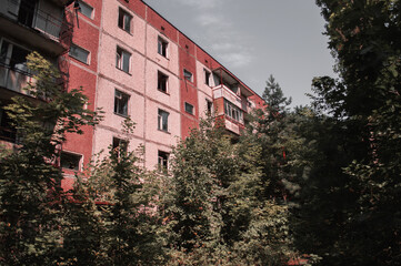 Fototapeta na wymiar A radioactive abandoned building overgrown with trees in the city of Pripyat