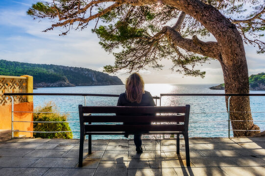 Spain, Mallorca, Sant Elm, woman sitting on bench, rear view
