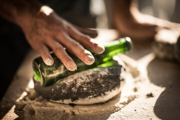 Man preparing black burger buns in kitchen, rolling dough with a bottle