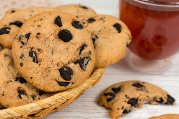 Chocolate cookies in a basket on the background of a glass cup of tea. Close-up.