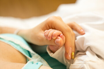Obraz na płótnie Canvas Close-up of tiny hand of newborn in mum's hand
