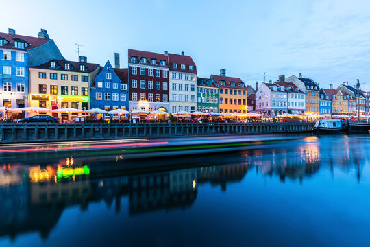 Denmark, Copenhagen, Light trails in front of row of colorful residential buildings standing along&Ocirc;&oslash;&Omega;Nyhavn harbor