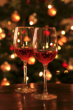 Rose wine in shiny wineglass in front of Christmas tree