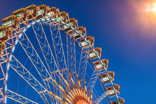 Germany, Bavaria, Munich, Low angle view of Ferris wheel glowing against clear sky at dusk