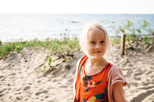 Blond girl standing at beach against Georgian Bay on sunny day