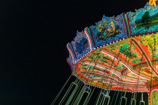 Germany, Bavaria, Munich, Chain swing carousel glowing against night sky