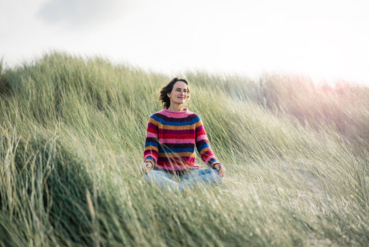 Mature woman relaxing on the beach, sitting in the dunes