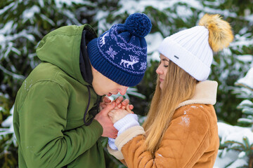 couple in love on date celebrate valentine's day, christmas, new year. guy girl hugging, warming frozen hands hot breath under fir tree in park winter holiday. young man woman wintertime on frost