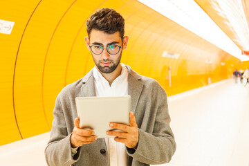 Germany, Munich, portrait of young businessman using digital tablet at underground station