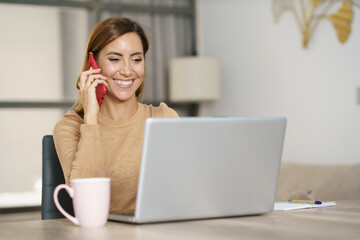 Businesswoman smiling while talking on phone at home