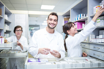 Smiling pharmacists working at cabinet in pharmacy