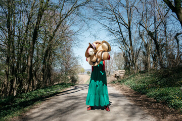 Woman hiding behind many straw hats