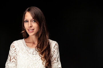 Portrait of young woman with long brown hair against black background