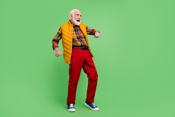 Photo of positive good mood senior gentleman wear yellow vest dancing smiling isolated green color background