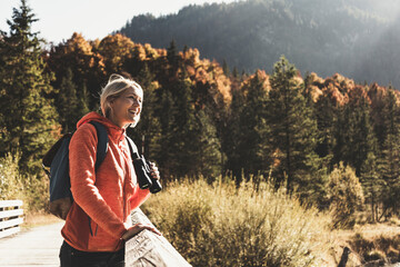Austria, Alps, woman on a hiking trip standing on a bridge with binoculars