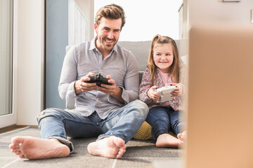 Young man and little girl playing computer game with gaming console