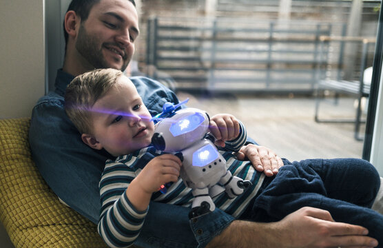 Father and son playing with a toy robot at home