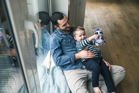Father and son playing with a toy robot at home