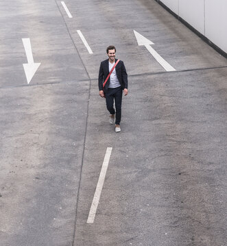 Confident businessman walking on road with arrow signs