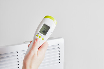 electric infrared thermometer for measuring surface temperature and air on the background of the electric radiator,