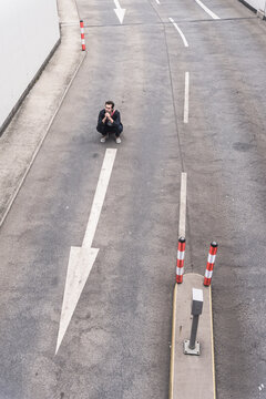 Businessman crouching on road with arrow sign
