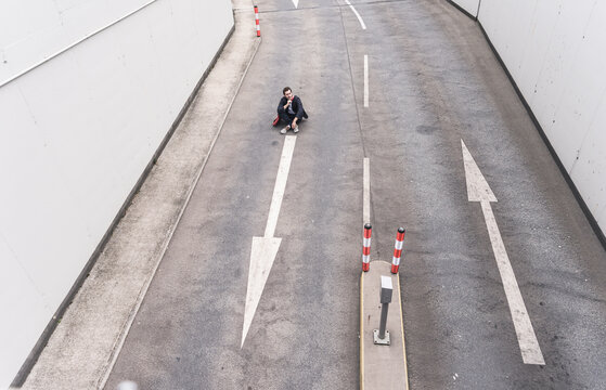 Businessman sitting on road with arrow signs