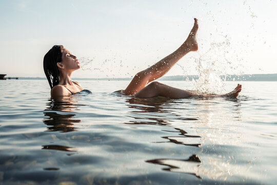 Young woman bathing in Lake Starnberg, splashing with water, Germany