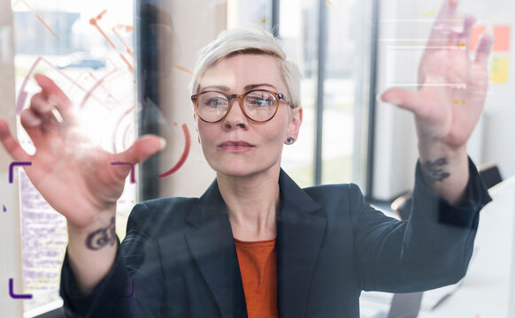 Businesswoman touching glass wall with data in office