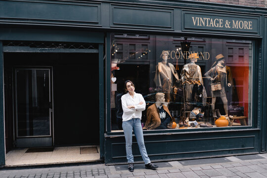 Full length of confident woman standing with arms crossed outside store