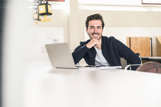Relaxed young businessman with laptop, sitting in office