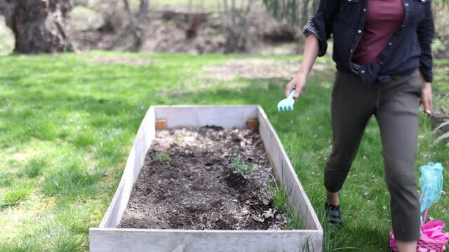 Beautiful brunette woman hiding easter eggs in an empty planter box