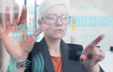 Businesswoman touching glass wall with data in office