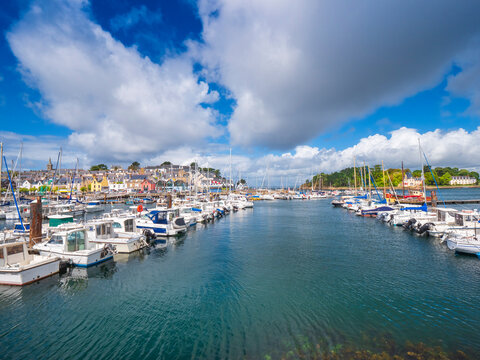 Boats moored at harbor against cloudy sky