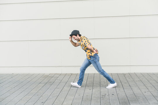 Young man wearing flat hat and aloa shirt, walking against headwind