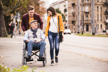 Happy senior man in wheelchair spending time with his grandchildren