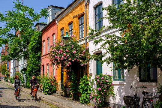 Denmark, Copenhagen, Man and woman riding bicycles along street of historical Nyboder district