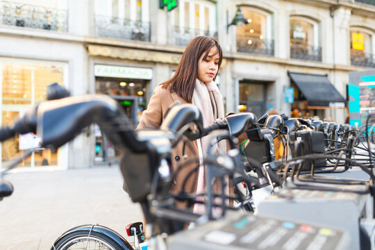 Spain, Madrid, young woman using rental bike in the city