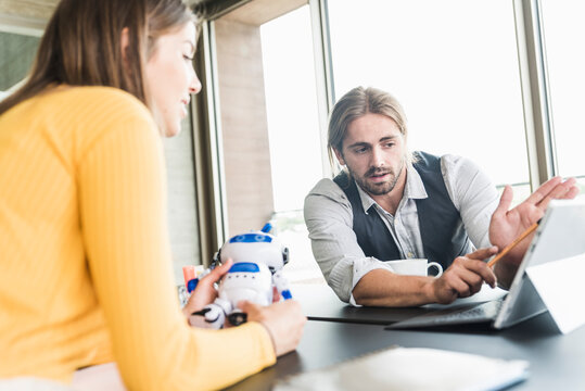 Young businessman and businesswoman using tablet at desk in office