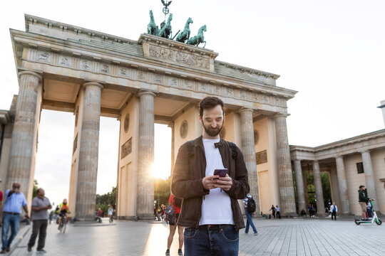 Man using smartphone in front of the Brandenburg Gate, Berlin, Germany