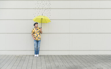 Digital composite of young man holding an umbrella at a wall with raindrops