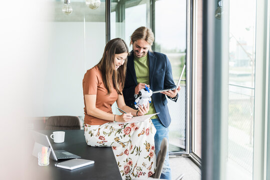 Young businesswoman and businessman working on robot in office