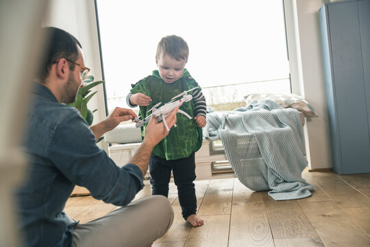 Boy in a costume and father playing with a drone at home